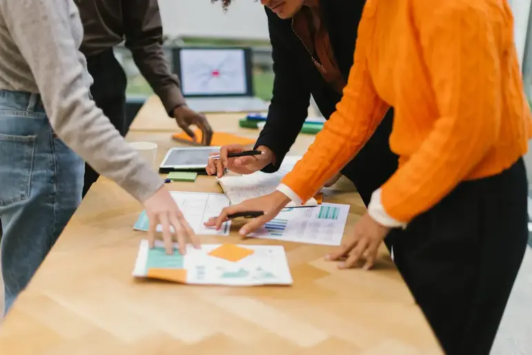 Equipo comercial ordenando reportes y notas sobre una mesa de trabajo